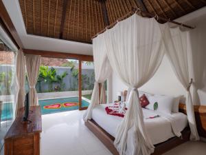 1 dormitorio con cama con dosel y piscina en Avery Le Nixsun Villas Uluwatu by Waringin Hospitality, en Uluwatu