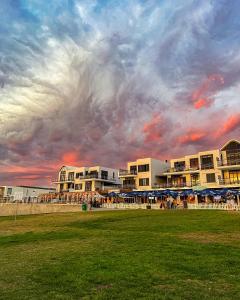 a group of buildings on the beach under a cloudy sky at 180 Eden on the Bay, Big Bay in Big Bay