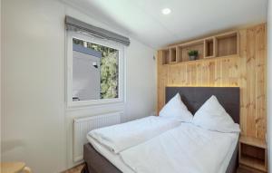 a bedroom with a bed with white sheets and a window at Tiny Haus 34 Am Brombachsee in Pleinfeld +30 photos