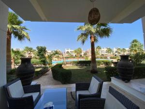 d'une terrasse avec des chaises, une table et des palmiers. dans l'établissement Renoviertes Luxusapartment Sunny Lakes 1 Sharm El-Sheikh nun auch für Langzeitmieter buchbar, à Charm el-Cheikh