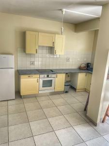 a kitchen with yellow cabinets and a white refrigerator at Rubis Appartement - Magnifique F3 in Sainte-Anne