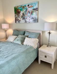 a bedroom with a bed with a painting on the wall at Top-floor beachside apartment with views in Casuarina +16 photos