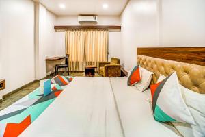 a hotel room with a large bed with colorful pillows at FabHotel Global Inn I Aurangabad Railway Station in Aurangabad