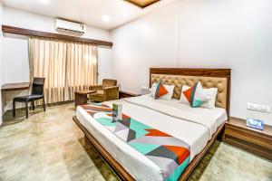 a bedroom with a large bed and a desk at FabHotel Global Inn I Aurangabad Railway Station in Aurangabad