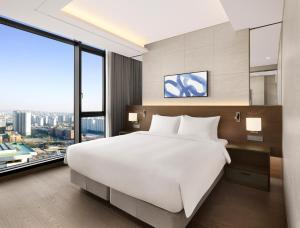 a bedroom with a large white bed and a large window at Four Points by Sheraton Suwon in Suwon