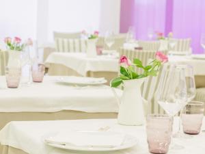 a white table with pink roses in a white vase at Hotel Sporting in San Benedetto del Tronto