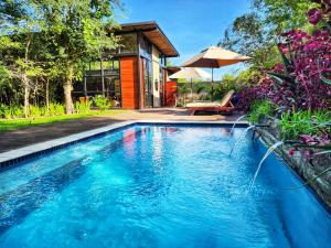 una piscina de agua azul frente a una casa en Mukwa River Lodge, en Livingstone