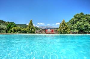 an island in the water with a red house in the background at La Ermita de los Llanos in Arenas de San Pedro