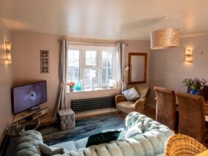 a living room with a couch and a tv at Blacksmiths Cottage in Uplyme