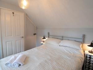a bedroom with a white bed with towels on it at Blacksmiths Cottage in Uplyme