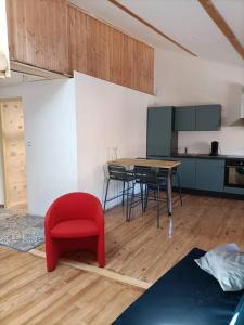 a living room with a red chair and a table at Superbe appartement au cœur du village in Largentière