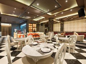 a restaurant with white tables and chairs and people in the background at Grace Hotel in Bangkok