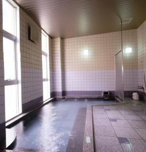 an empty room with ailed floor and white tiled walls at Hotel Daisen Shirogane in Daisen