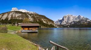 a cabin on a lake with mountains in the background at Ferienwohnung Werner Pucher OG in Altaussee