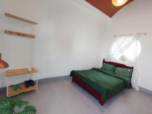 Un dormitorio con una cama verde y una ventana en Nhà bốn chín, en Ấp Khánh Phước (1)