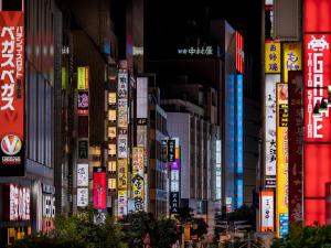 un gruppo di edifici con cartelli in città di COCOSHUKU Shinjuku-Hanazono a Tokyo