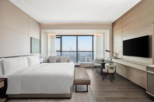ein Hotelzimmer mit einem großen Bett und einem TV in der Unterkunft JW Marriott Hotel Changsha in Changsha