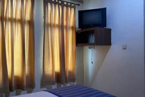 - une chambre avec une télévision, un lit et des rideaux dans l'établissement OYO 92342 Hotel Batik Traveller, à Medan