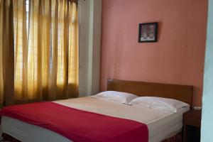 Ce lit se trouve dans une chambre dotée d'un mur rouge. dans l'établissement OYO 92342 Hotel Batik Traveller, à Medan