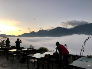 um grupo de pessoas de pé em mesas com vista para um lago em Fansipan Terrace Cafe and Homestay em Sapa