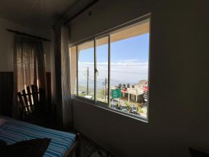 een slaapkamer met een raam met uitzicht op de oceaan bij Lakshan View Resort in Haputale