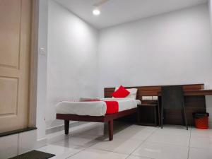 a bedroom with a bed with a red pillow on it at Kings Fort Rooms Thrippunithura in Ernakulam
