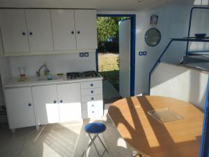 eine Küche mit weißen Schränken, einem Tisch und einem Esszimmer in der Unterkunft Maison flottante sur la seille in Cuisery