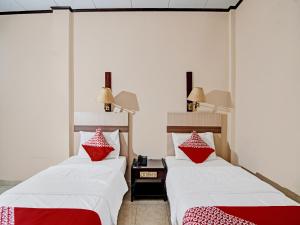 two beds in a room with red and white pillows at OYO 92330 Hotel Rindu Sempadan in Pekanbaru
