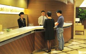 a group of people standing at a reception counter at Shenzhen Shekou Honlux Apartment (Sea World) in Shenzhen
