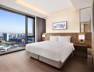 Four Points by Sheraton Suwon في سوون: غرفة نوم بسرير ابيض كبير ونافذة كبيرة