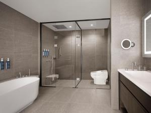 a bathroom with a shower and a tub and a toilet at Four Points by Sheraton Suwon in Suwon