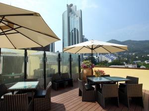 two tables and chairs with umbrellas on a balcony at Shenzhen Shekou Honlux Apartment (Sea World) in Shenzhen