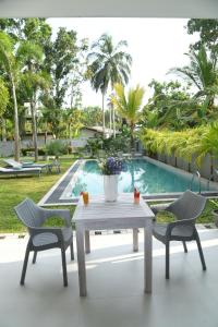 a white table and two chairs and a swimming pool at Eldezo Relax Paradise (Pvt) Ltd in Bentota