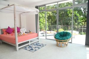 a bedroom with a bed and a chair and windows at Eldezo Relax Paradise (Pvt) Ltd in Bentota