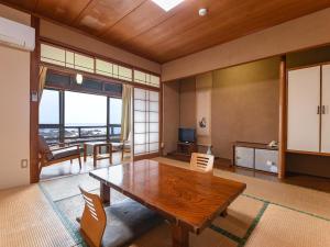 ein Wohnzimmer mit einem Holztisch und einem großen Fenster in der Unterkunft Misaki Kanko Hotel in Muroto