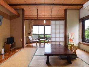 una sala de estar con una gran mesa de madera y sillas en Misaki Kanko Hotel, en Muroto