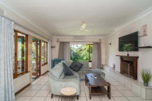 een woonkamer met een bank en een tv bij Spacious retreat with large pool and lush garden in Pinetown