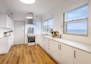 cocina con armarios blancos y ventana grande en Glenelg Beach House With Private Beachfront Pool, en Glenelg