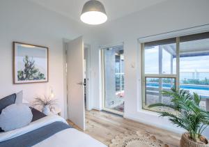 a bedroom with a bed and a large window at Glenelg Beach House With Private Beachfront Pool in Glenelg