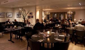 a group of people sitting at tables in a restaurant at Sølvgarden Motell in Rysstad