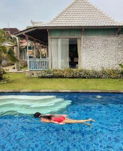 a woman is laying in a swimming pool at Casa Batu Belig in Seminyak