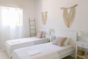 two beds in a room with white walls and a window at Casa Yasmina in Katastárion