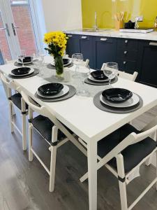 einen weißen Tisch mit Stühlen, Tellern und Weingläsern in der Unterkunft Luxury home in Anfield in Liverpool