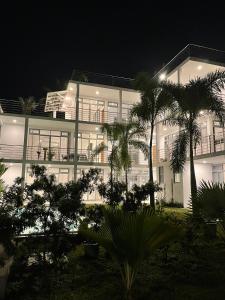 a large white building with palm trees in front of it at Eldezo Relax Paradise (Pvt) Ltd in Bentota