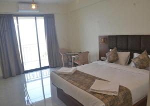 una habitación de hotel con una cama grande y una mesa en Hotel Brilliant Panchgani en Pānchgani