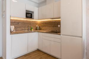 a white kitchen with white cabinets and a sink at 6 Islands - Holiday & Business Apartments - free garage parking in Split
