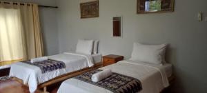 a hotel room with two beds and a window at Selong Belanak Bungalows in Selong Belanak