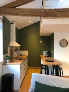 uma cozinha com paredes verdes e uma mesa com bancos em Gites De la Cour au Grenier em Chauvigny