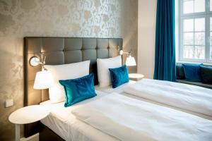 a bedroom with a large bed with blue pillows at Motel One Magdeburg in Magdeburg