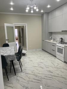 a kitchen with white cabinets and a table and chairs at 1 комн квартира in Oral
